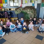 grupa dzieci siedzi przy dinozaurze.jpg