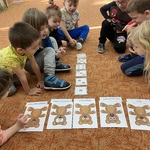 Dzieci siedzą na dywanie i przeliczają liczmany z misiami .JPG