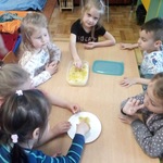 Dzieci przy stoliku jedzą miód z plastra.JPG