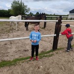 chłopiec stoi przy zagrodzie z końmi.jpg