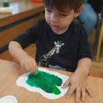 chłopiec maluje drzewo zieloną farbą.jpg